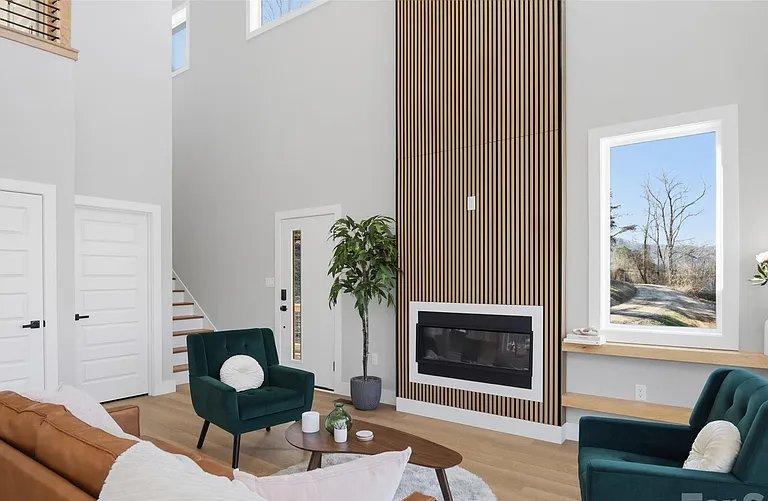Open-concept living room and kitchen with a white island, pendant lighting, and a staircase with wood treads.